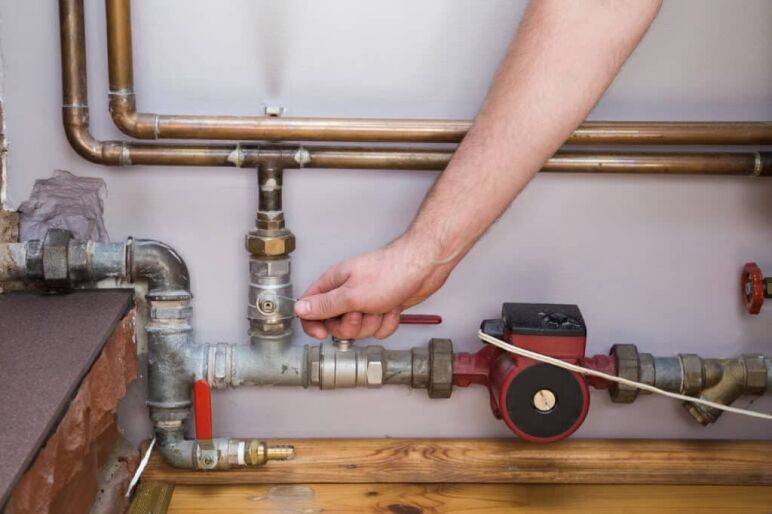 Man working at pipes. employee's hand turning on or turning off water supply in the boiler room. commercial plumbing com
